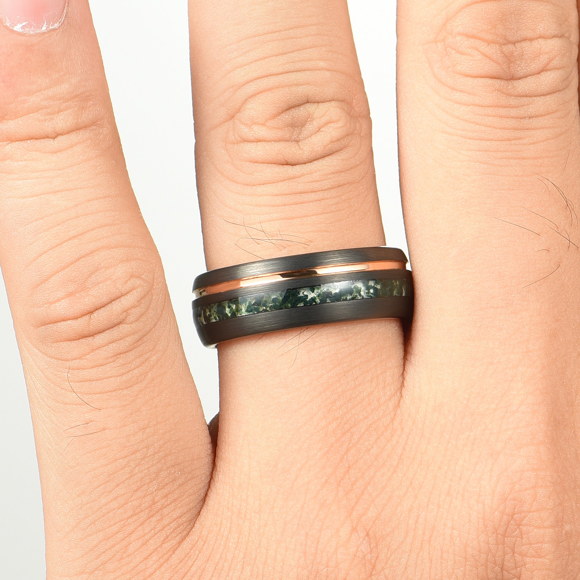 Black ring with moss agate on a person's finger against a white background