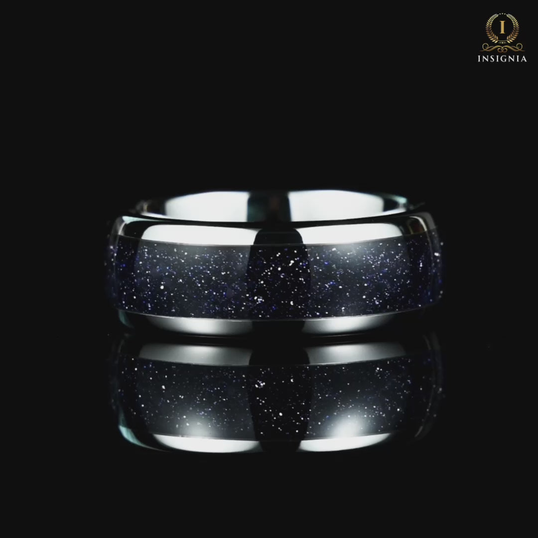 A video of a silver wedding band rotating on a reflective black glass surface, showcasing its elegant design details.