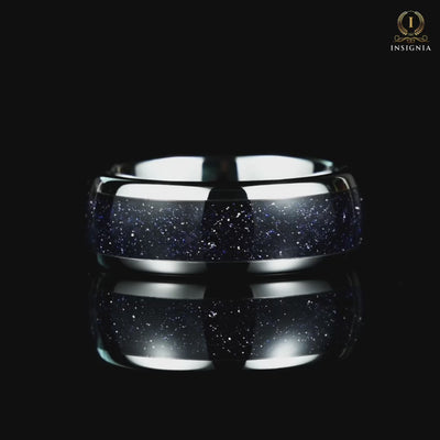 A video of a silver wedding band rotating on a reflective black glass surface, showcasing its elegant design details.