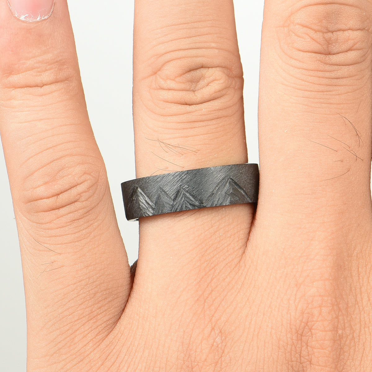 Zirconium ring with hand-carved mountain range shown on hand
